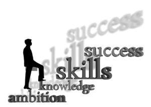 A silhouette of a man walking up a set of stairs made from the following words ambition knowledge skills success